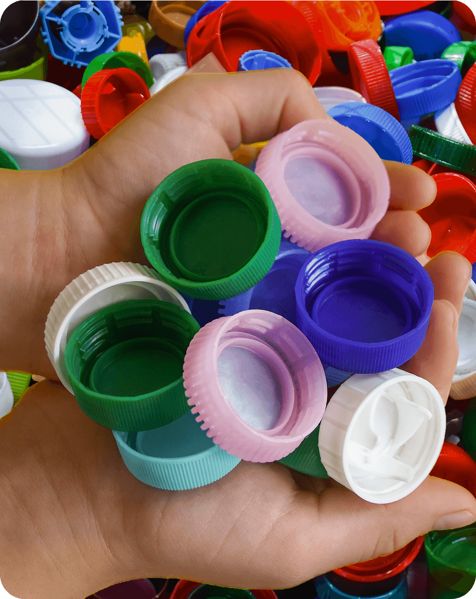 Mãos segurando tampinhas plásticas coloridas